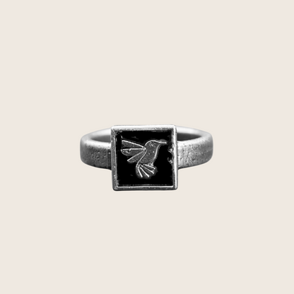 Silver ring with a square black stone featuring a bird design on a white background